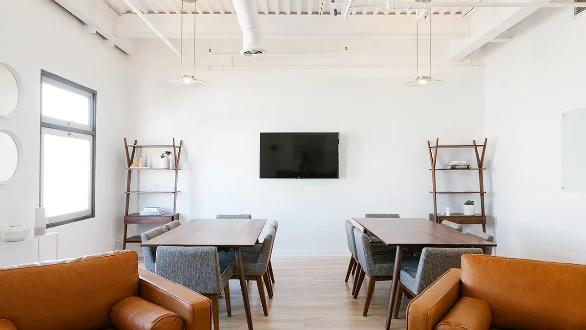 Espace de travail avec deux fauteuils en cuir au premier plan et des tables de réunion au fond